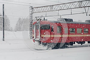 The red train was driving in the snow