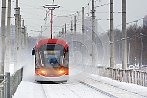 Red tram rushes during a winter snowstorm in the city