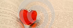 Red transparent glass heart lay in a book