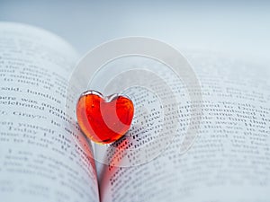 Red transparent glass heart lay in a book