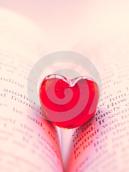 Red transparent glass heart lay in a book