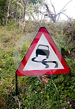 A red triangle driving sign on the side of road