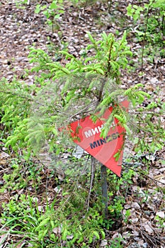 Red triangle mine warning sign in the forest