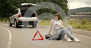 Red triangle sign behind the woman near broken car