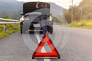 Red triangle sign on road for warning have car with breakdown open car hood and man fixing a car