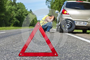 Red triangle sign and Sad man after car breakdown