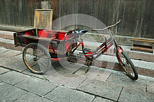 Red tricycle parked in a deserted street of Fenghuang