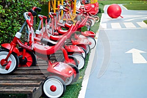 Red tricycles line up beside a track in a children\'s playground area