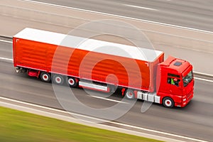 Red truck on blurry asphalt road rushes at high speed