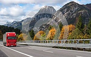 Red truck driving on the highway in the Alps.