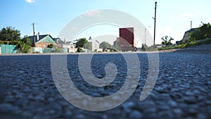 Red truck goes at the asphalt road. Car is driving at the highway in the summer evening. Traffic close up. Bottom view