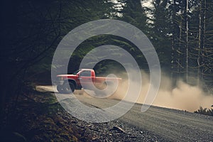 red truck speeding on a gravel forest road, dust trailing
