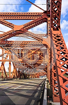 Red truss Broadway drawbridge across Willamette River in Portland down Town at sunny day with cloud sky