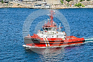 Red tugboat goes for a mission from the harbour out to sea