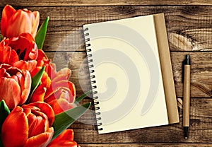 Red tulip flowers with notebook and pen