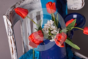 Red tulips bouquet in blue vase on vintage cher
