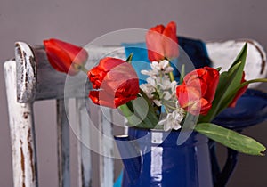 Red tulips bouquet in blue vase on vintage cher