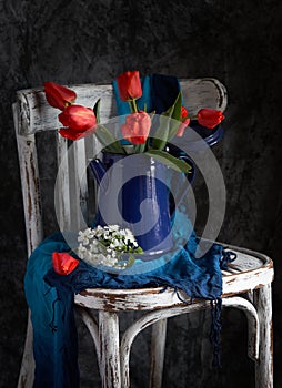 Red tulips bouquet in blue vase on vintage cher.