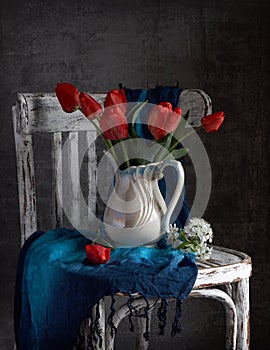 Red tulips bouquet in white vase on vintage cher.