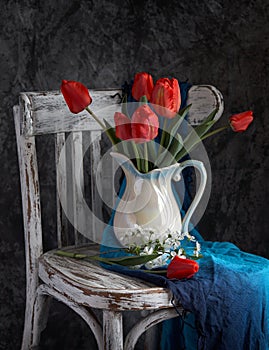 Red tulips bouquet in white vase on vintage cher