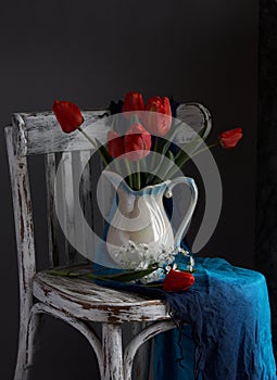 Red tulips bouquet in white vase on vintage cher