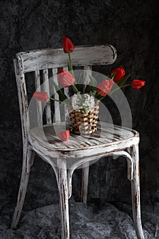 Red tulips bouquet in wooden vase on vintage cher.