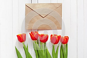 Red tulips and a card in an envelope