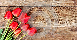 Red tulips flowers on a brown wooden background with a copy space.