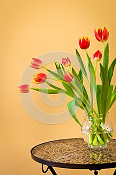 Red tulips in a vase on mosaic table.