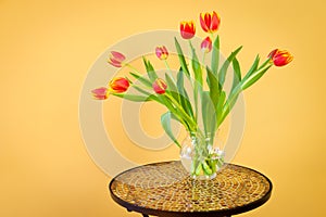 Red tulips in a vase on mosaic table.