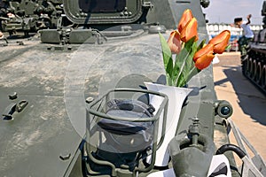 Red tulips in a vase stand on an armoured infantry fighting vehicle