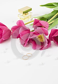 Red tulips, wedding rings, perfume and bead