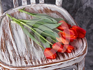 Red tulips on a wooden vintage old chair