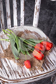 Red tulips on a wooden vintage old chair