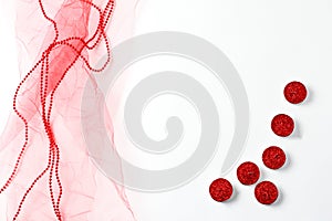 Red tulle, candles and beads on a white background. flat lay composition