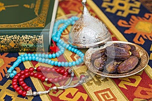 Red and turquoise rosaries, dates, and qur`an
