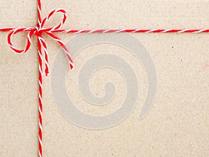 Red twine string tied in a bow on paper backdrop.