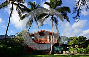 Red Two Story Beach House with tall coconut trees