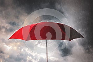 Red umbrella against the storm,sky background and black cloud group and rain, preventing rain and wind hazards,saving planning,