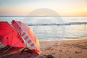 Red umbrella on the beach among  sunset on the sea