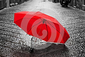 Red umbrella on cobblestone street in the old town. Wind and rain