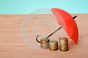 Red umbrella and coins with copy space. Money protection and safety assurance concept