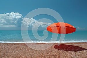 A red umbrella on a deserted beach against the background of the sea