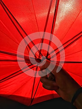 Red umbrella grabbed by a hand to block sunlight.