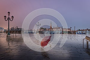 Red umbrella in rainy early morning in Venice