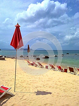 Red umbrella and red chairs on a sea beach