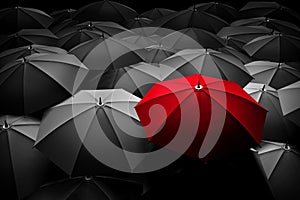 Červený dáždnik vyčnievať z davu mnohých čierne a biele dáždniky.