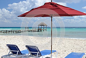 Red umbrella and sunbeds on the beach.