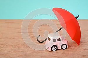 Red umbrella and toy car with copy space.Car protection and safety assurance concept