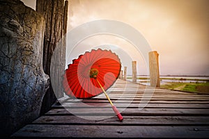 Red umbrella on U Bein bridge on sunrise in Mandalay